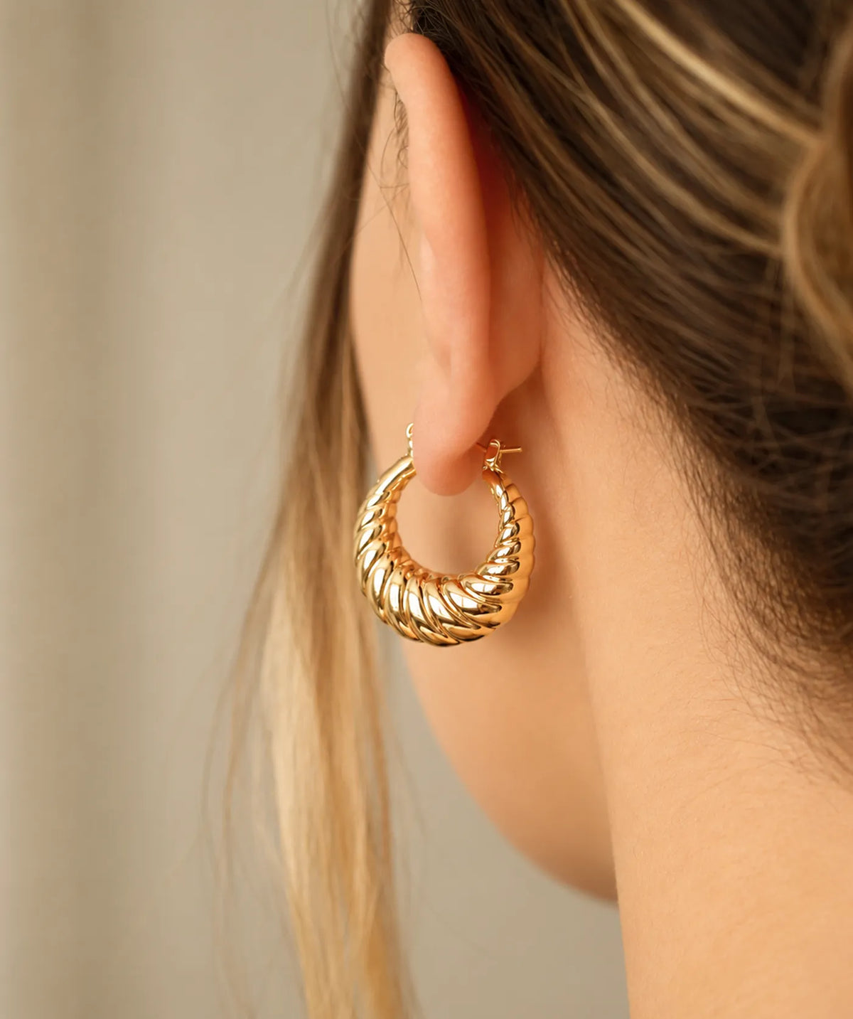 Model wearing the Gold Chunky Oval Croissant Hoop Earrings on the ear