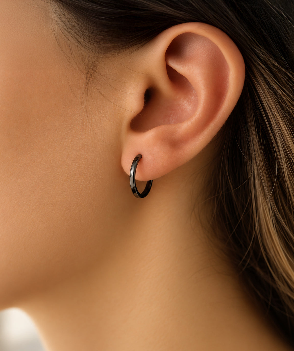 Model wearing the Black Flat Sleeper Hoop Earrings on the ear