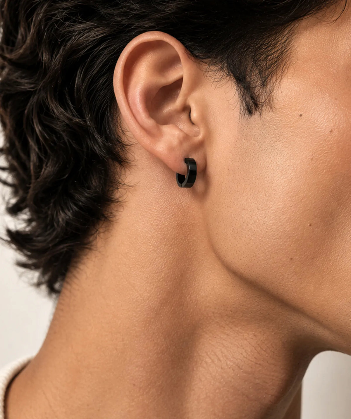 Man wearing the Black Thick Round Flat Hoop Earrings on the ear