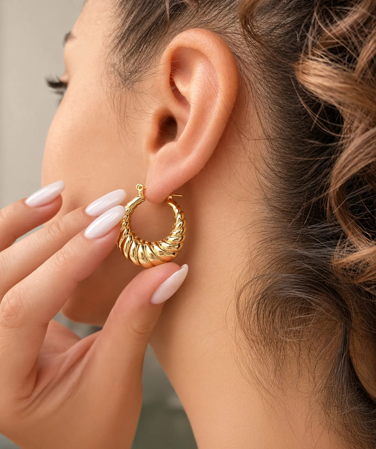 Model wearing the Gold Chunky Oval Croissant Hoop Earrings on the ear