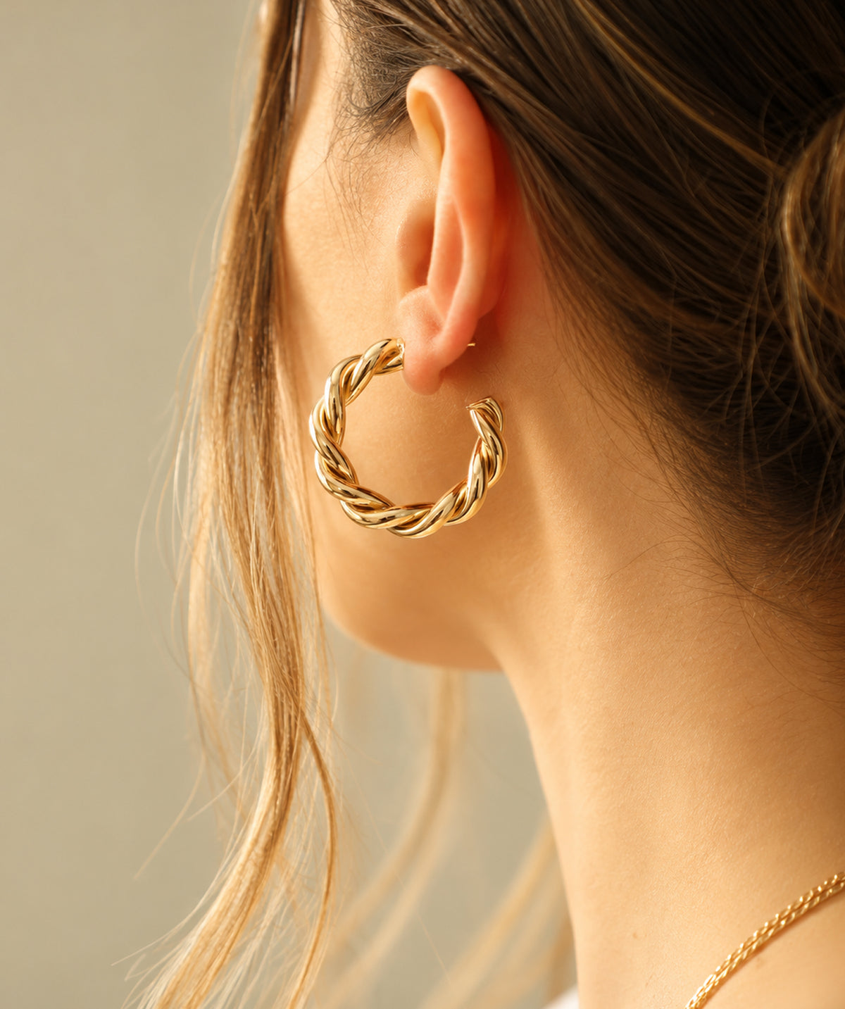 Model wearing the Gold Open Twist Hoop Earrings on the ear