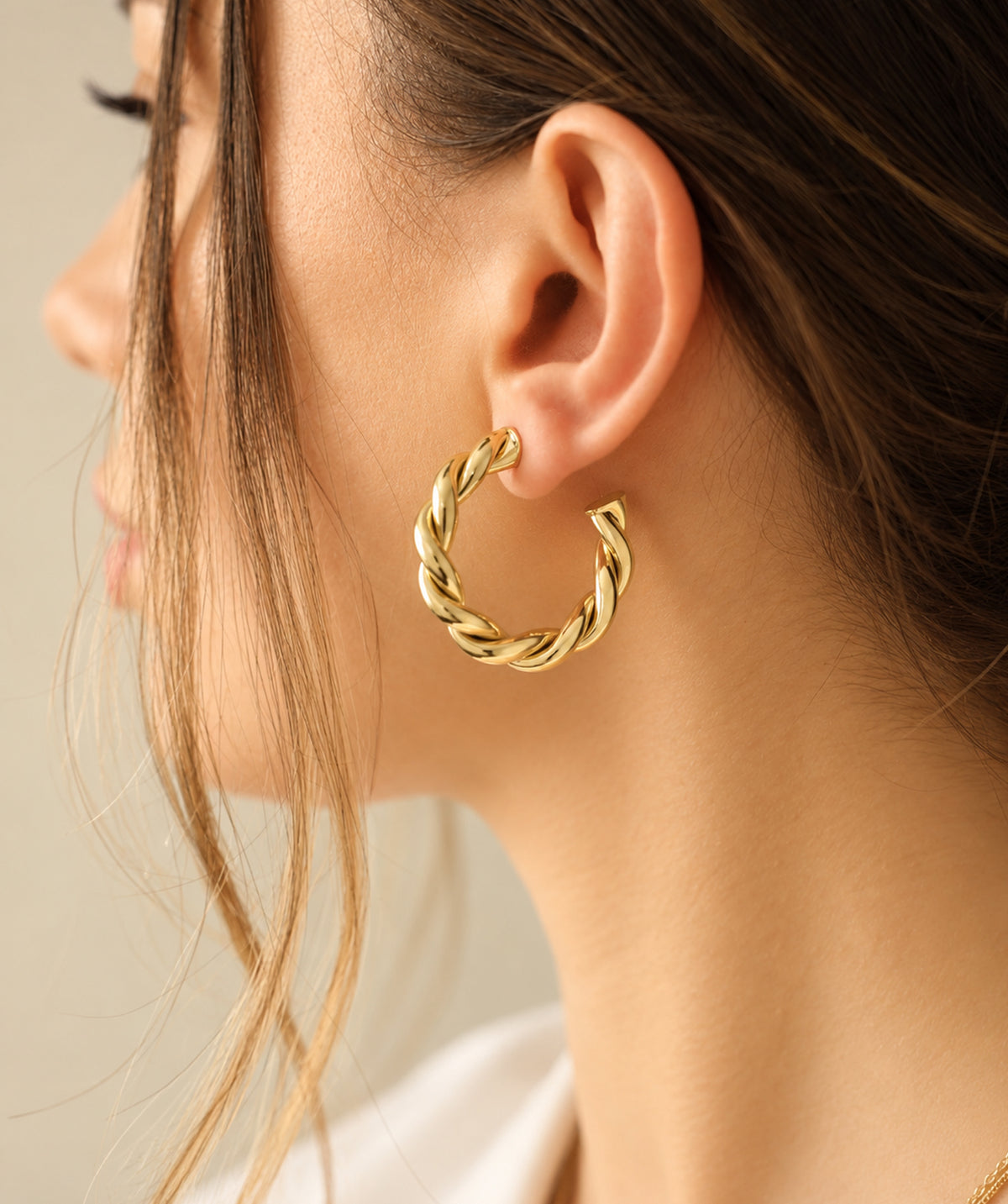 Model wearing the Gold Open Twist Hoop Earrings on the ear