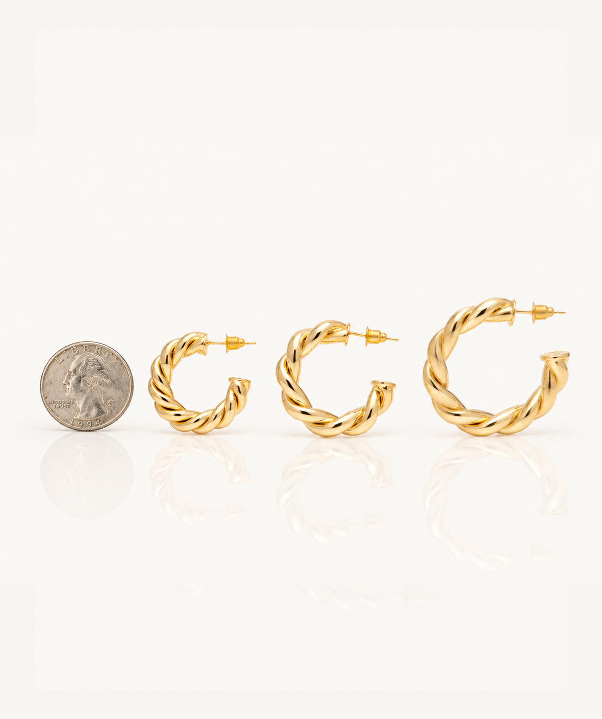 Gold Open Twist Hoop Earrings next to a coin for size reference